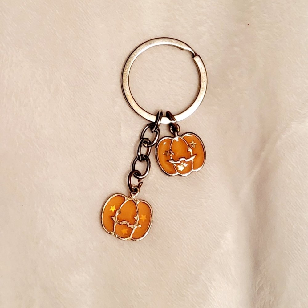 Quarter-sized keychain adorned with two vibrant orange pumpkin charms.